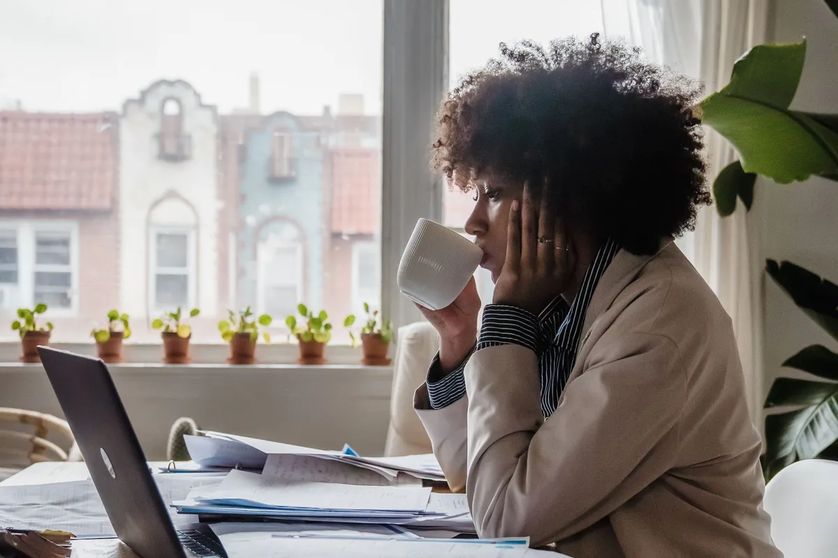 A consultant working through papers and a laptop at a home-office desk