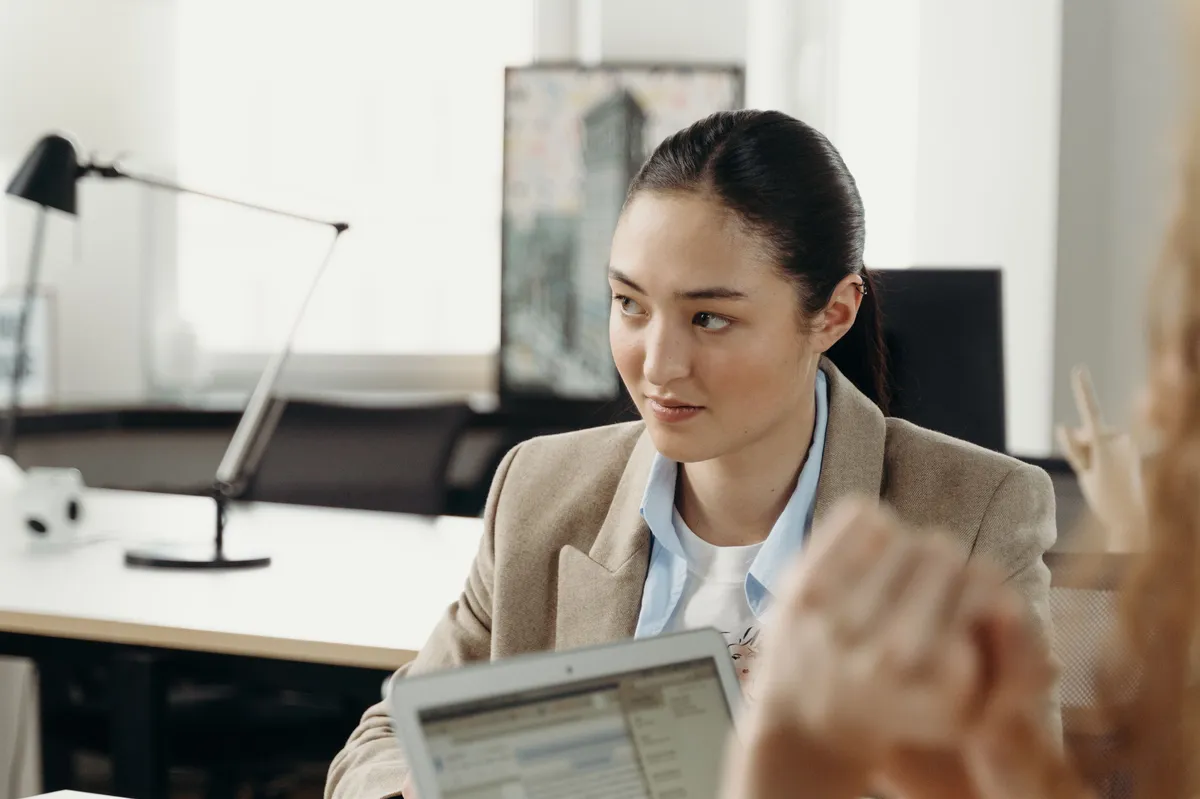 A program manager in conversation at her laptop in a bright office